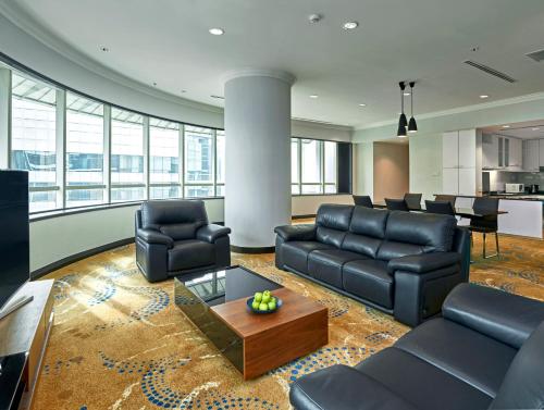 a living room with black leather furniture and a table at Pullman Kuala Lumpur City Centre Hotel & Residences in Kuala Lumpur
