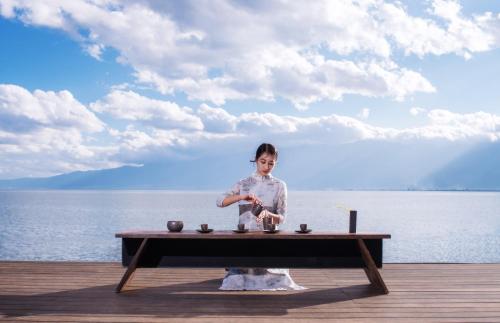 a woman standing on a table near the water at Yakamoz Erhai Hotel in Dali