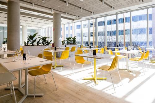 a cafeteria with white tables and yellow chairs at ibis Styles East Perth in Perth