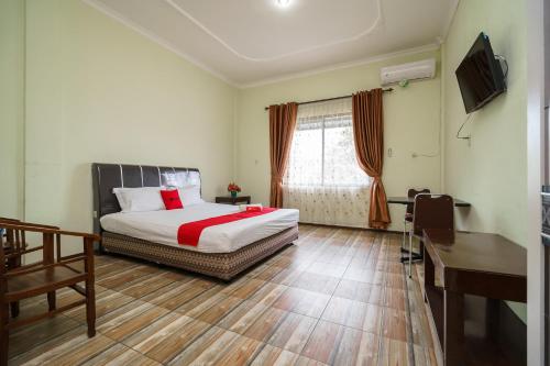 a bedroom with a bed and a desk and a window at RedDoorz @ Pematangsiantar in Pematangsiantar