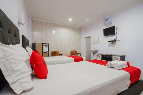 a bedroom with two beds with red and white sheets at RedDoorz near Danau Toba Parapat in Parapat