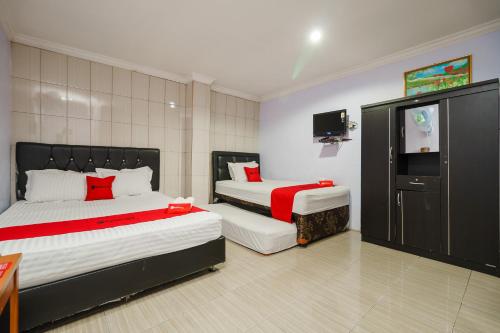 a bedroom with two beds and a flat screen tv at RedDoorz at Sedayu 2 Near Danau Toba Parapat in Parapat