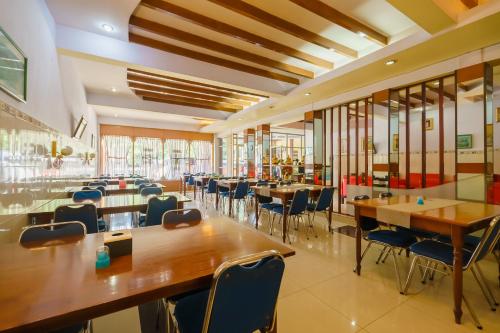 a restaurant with wooden tables and chairs and windows at RedDoorz at Sedayu 1 Parapat in Parapat