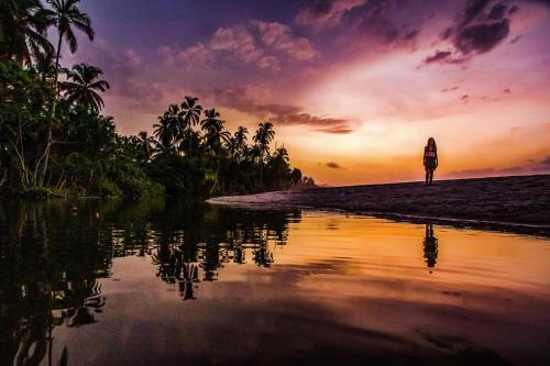 a woman walking on the beach at sunset at Palomino Hostel in Palomino