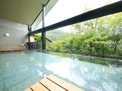 an indoor swimming pool with a view of trees at Shimoda Central Hotel in Shimoda