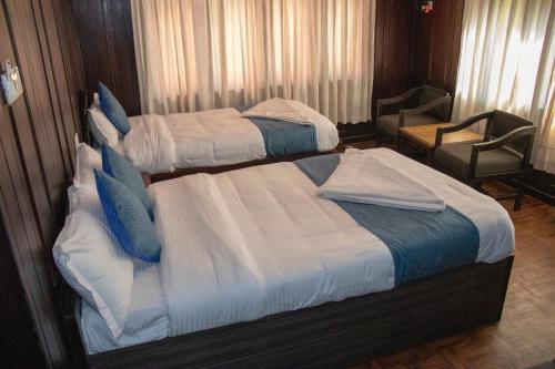 two twin beds in a hotel room with a chair at Hotel Green Horizon in Kathmandu