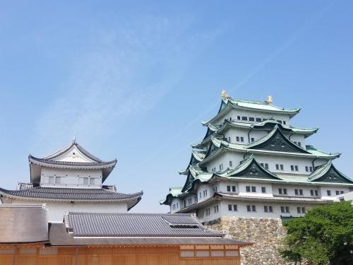 two tall japanese buildings with a blue sky in the background at Sotetsu Fresa Inn Nagoya Sakuradoriguchi in Nagoya