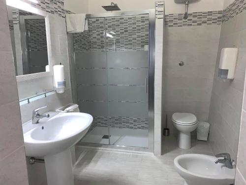 a bathroom with a shower and a sink and a toilet at Hotel Villaggio Ristorante Pizzeria Museo TANIT in Carbonia