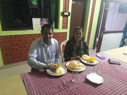 Um homem e uma mulher sentados à mesa com comida. em Quadriya Palace em Thekkady