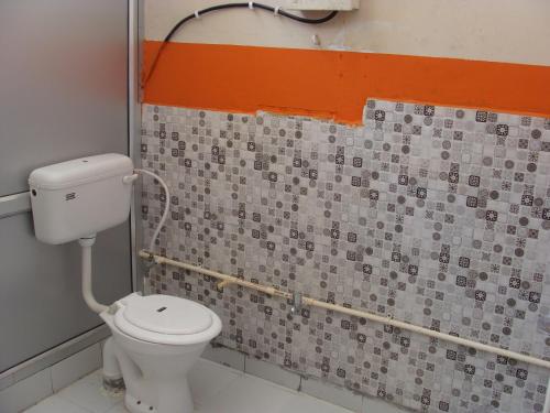a bathroom with a toilet and a tiled wall at Hotel Abhinandan Grand in Dehradun