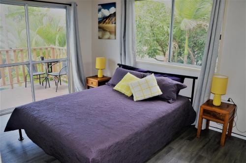 a bedroom with a purple bed with two lamps and a balcony at Pippies Beachhouse Backpackers in Rainbow Beach