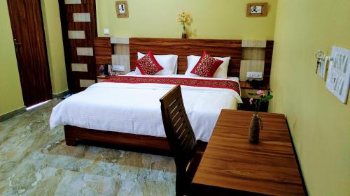 a bedroom with a large bed and a wooden table at Sakura Guest House in Dharamshala