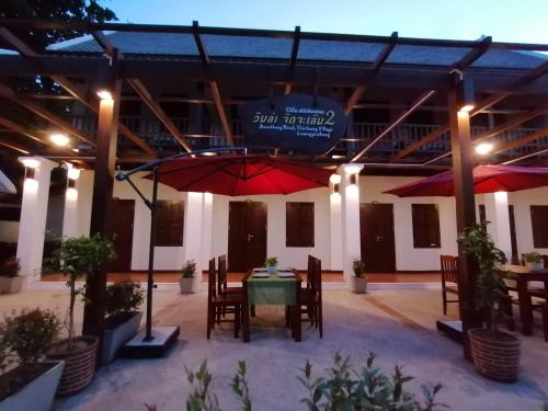 a patio with a table and chairs and an umbrella at Villa Chitchareune 2 in Luang Prabang