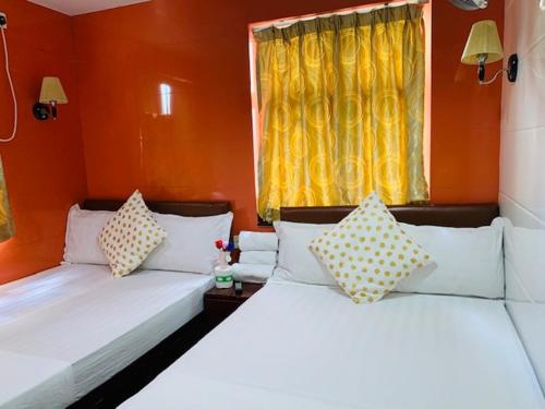2 camas en una habitación con paredes de color naranja en Woodstock Hostel, en Hong Kong