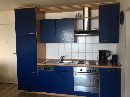 eine Küche mit blauen Schränken und einem Waschbecken in der Unterkunft Blaumuschel Lubmin, Wohnung 9 in Lubmin