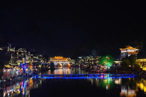 a city lit up at night with a river at BaHaoBieYuan in Fenghuang