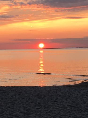 einen Sonnenuntergang am Strand mit der Sonne, die im Wasser reflektiert in der Unterkunft Blaumuschel Lubmin, Wohnung 9 in Lubmin