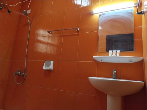 baño de azulejos de color naranja con lavabo y espejo en Super OYO 107 Al Areen Hotel Apartments, en Shāhiq