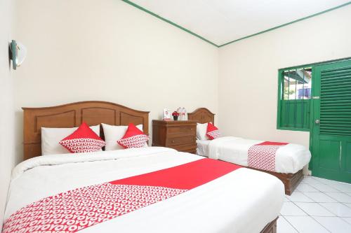1 dormitorio con 2 camas y almohadas rojas y blancas en SUPER OYO 1959 Penginapan Kepurun Pawana Indonesia, en Sleman