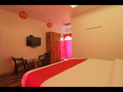 a bedroom with a bed and a table and a tv at Sunset Valley Holiday Inn in Ooty