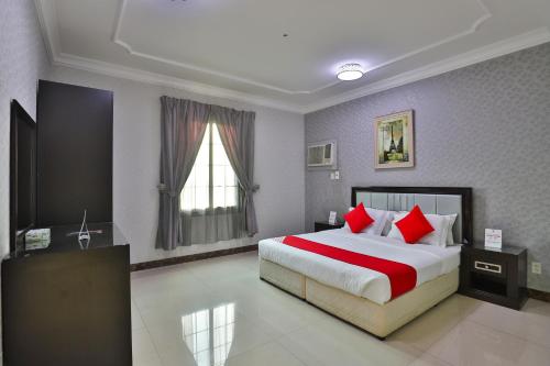 Jubail High Rise Hotel في الجبيل: غرفة نوم بسرير كبير ومخدات حمراء