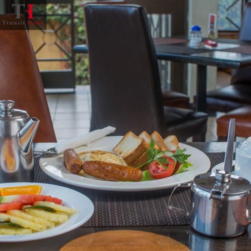 un piatto di alimenti con salsiccia e verdure su un tavolo di Nairobi Transit Hotel a Nairobi