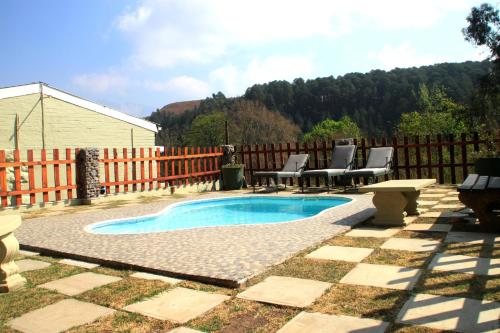 uma piscina num quintal com cadeiras e uma mesa em Gooderson Leisure Mountain View Cottages Self Catering and Timeshare Resort em Drakensberg Garden