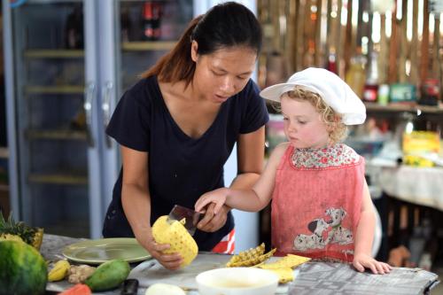 a woman and a little girl preparing food in a kitchen at Mr. Chuoi Bar and Hut in Ko Phra Thong