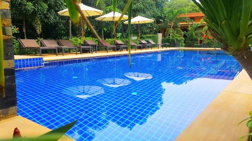 a large blue swimming pool with chairs and umbrellas at Lanta Riviera Villa Resort - SHA Certified in Ko Lanta
