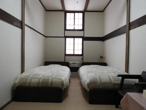 two beds in a room with two windows at Brocken Hutte in Hakuba