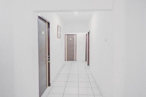 an empty corridor with white walls and white floors and doors at RedDoorz @ Jalan Hayam Wuruk Lampung 2 in Bandar Lampung