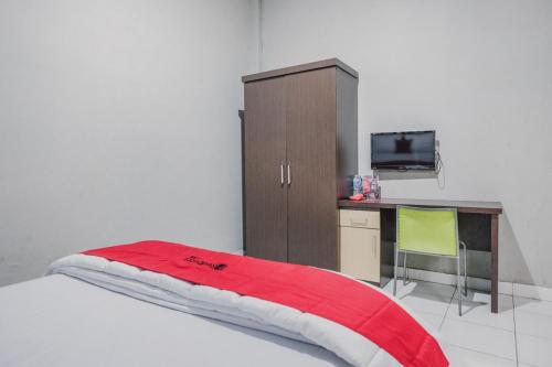 a bedroom with a bed with a desk and a cabinet at RedDoorz @ Jalan Hayam Wuruk Lampung 2 in Bandar Lampung