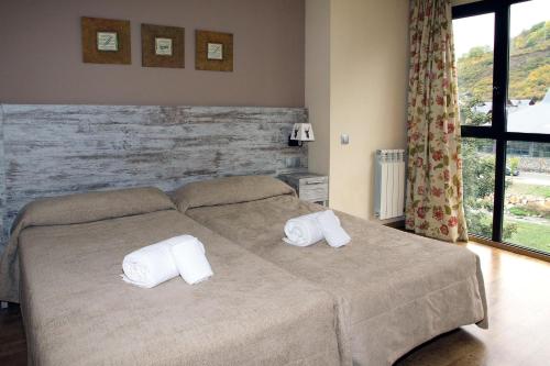 a bedroom with a bed with two towels on it at Aparthotel La Vall Blanca in Vielha
