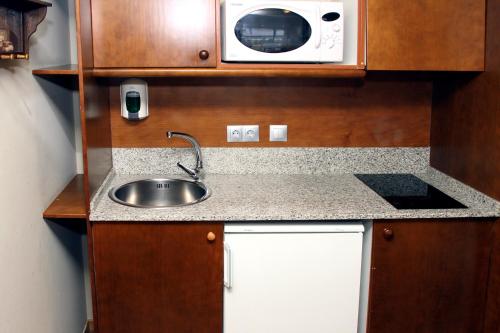 
a kitchen with a microwave, sink, and dishwasher at Aparthotel La Vall Blanca in Vielha
