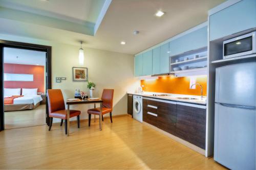 a kitchen with a table and chairs and a bed at Aspen Suites Hotel Sukhumvit 2 in Bangkok