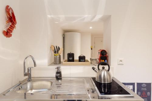 a kitchen with a sink and a tea kettle on the stove at Travel Homes - L'Arsenal, studios en hyper centre in Mulhouse