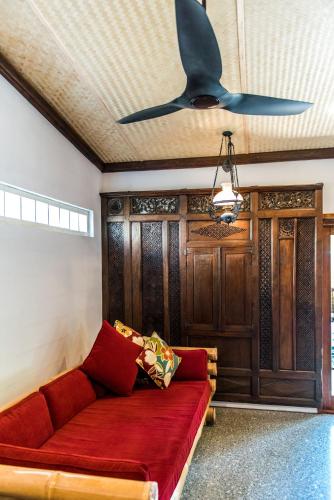 a living room with a red couch and a ceiling fan at Bali at the Bay in Nelson Bay