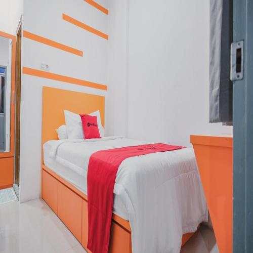 a bedroom with a bed with a red blanket on it at RedDoorz @ Jalan Sukabangun 2 Palembang in Palembang