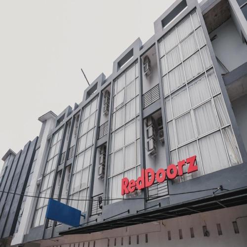 un edificio con un cartello rosso sul lato di RedDoorz @ Jalan Sukabangun 2 Palembang a Palembang