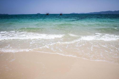 a sandy beach with two boats in the ocean at Coto Center Homestay in Dao Co To