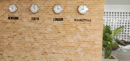 a wall with clocks on a brick wall at Proud Khaoyai in Pak Chong