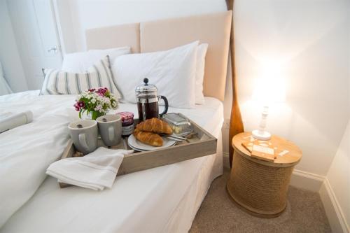 a tray with pastries and coffee on a bed at Beach House No1 With Amazing Sea Views And Direct Beach Access in Fairlie