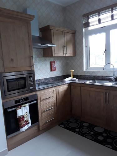 a kitchen with wooden cabinets and a microwave at Maison Cattleya Selfcatering Apartment in Mahe