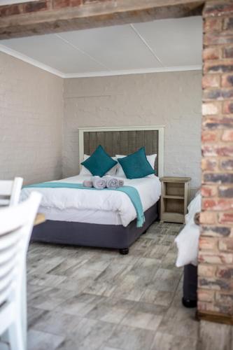 a bedroom with a large bed with blue pillows at Opstal Guestfarm in Potchefstroom