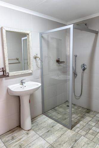 a white bathroom with a shower and a sink at Opstal Guestfarm in Potchefstroom