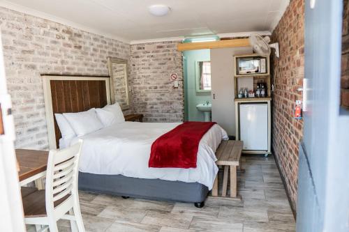 a bedroom with a bed with a red blanket on it at Opstal Guestfarm in Potchefstroom