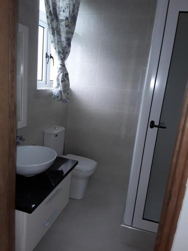 a white bathroom with a sink and a toilet at Maison Cattleya Selfcatering Apartment in Mahe