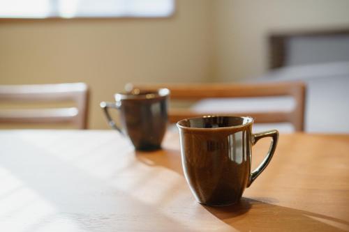 two coffee cups sitting on a wooden table at Coto in Miyazu