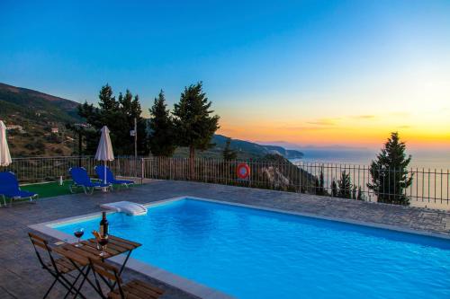 a swimming pool with a table and chairs and a sunset at Ble on Blue in Athanion