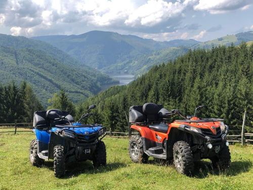 two atvs parked on top of a hill with mountains at Hotel Popasul Regelui Transalpina in Tău Bistra